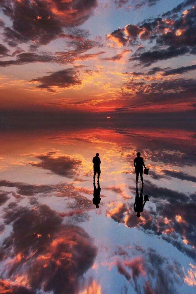 Siluetas de viajeros sobre el salar reflejando el atardecer